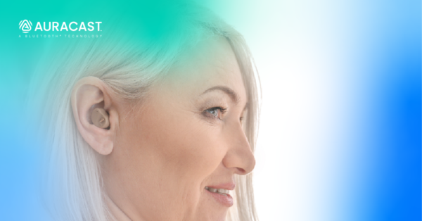 A woman using a beige hearing aid, with blue and green atmospheric colors around her and the Auracast logo in the upper left.