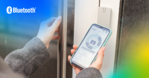 Close up view of a person holding a smart phone running a digital key application to wirelessly unlock the door in front of it.