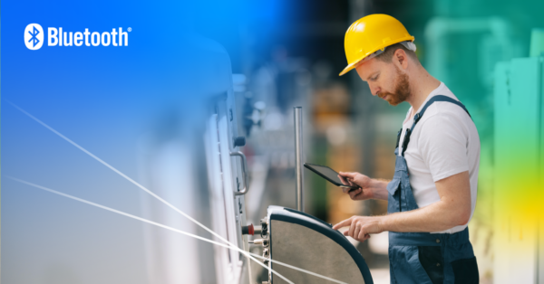 A worker in a hard hat and overalls uses a Bluetooth enabled tablet to control and monitor machinery.