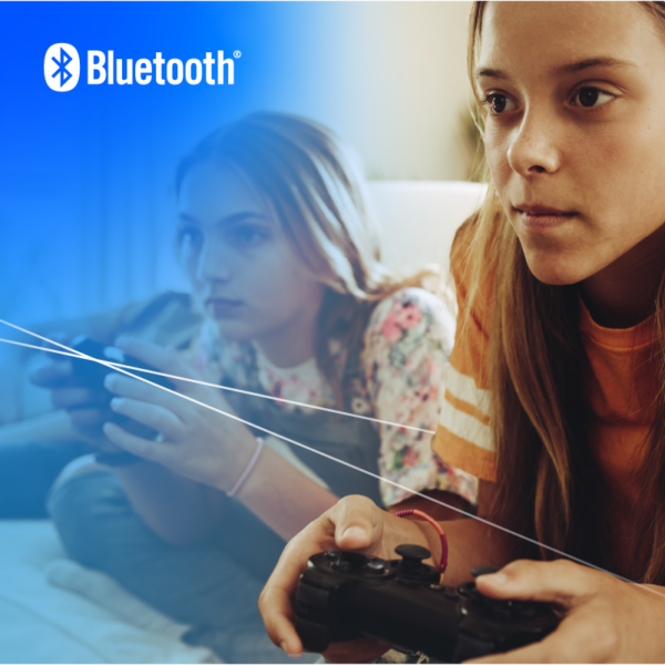 Two girls look forward intently, playing video games with wireless gaming controllers.