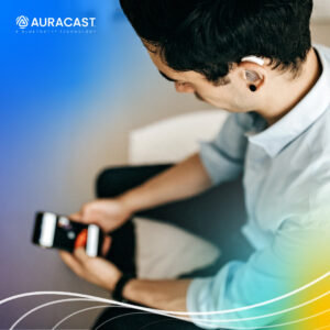 An overhead view of a person using hearing aids and holding a smartphone, using Bluetooth LE Audio and Auracast broadcast audio to wirelessly connect and stream audio.